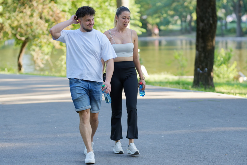9 - A couple walking together along a paved path in a park with a lake